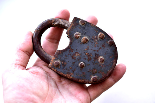 An old padlock in his hand on a white background