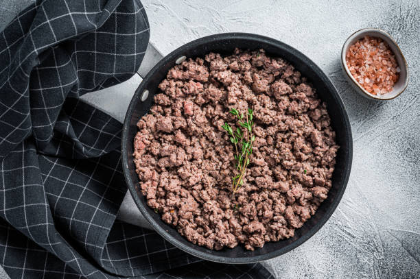 istock Fried mince beef and lamb meat in a pan with herbs. White background. Top view 1303679989