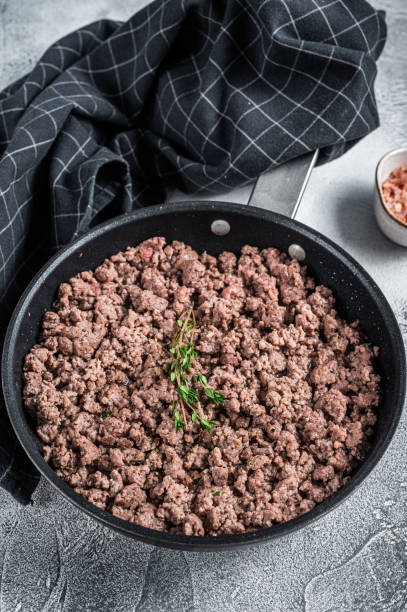 istock Fried mince beef and lamb meat in a pan with herbs. White background. Top view 1303680039