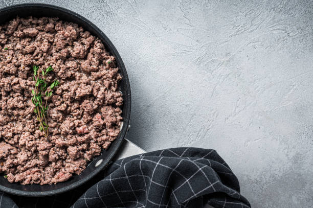 istock Fried ground mince beef and pork meat in a pan with herbs. White background. Top view. Copy space 1303680083