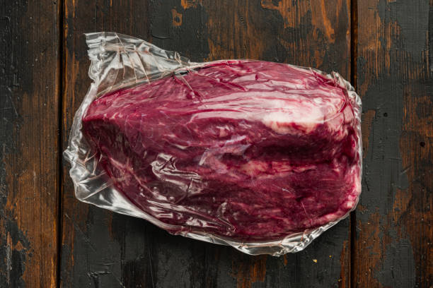 beef cut in vacuum, on old dark  wooden table background - airtight packing meat food imagens e fotografias de stock