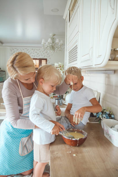 istock Mom with two sons cooking holiday pie in the kitchen. 1303681836