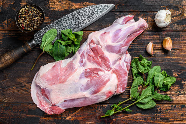 ニンニク、ミントと全体の生の子羊の肩の脚の肉。暗い木製の背景。トップビュー - dead animal butcher meat sheep ストックフォトと画像