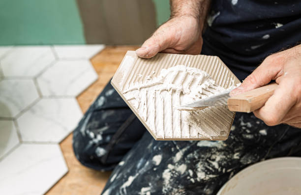 renovación del baño - trabajador (tiler) esparciendo adhesivo antes de colocar azulejos cerámicos - tile adhesive fotografías e imágenes de stock