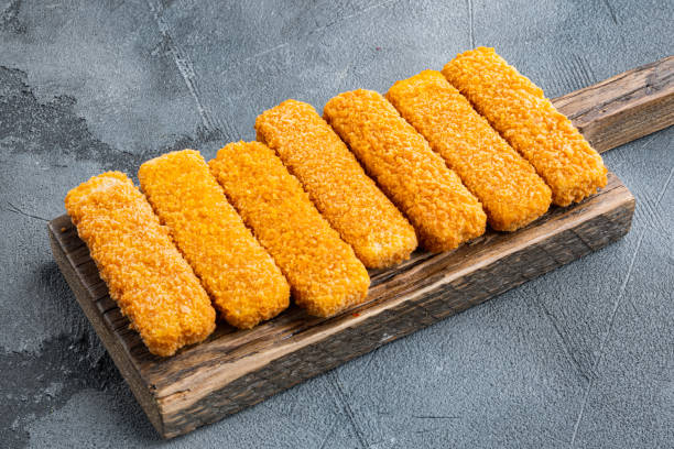 Photo of Frozen fish fingers, on wooden cutting board, on gray background