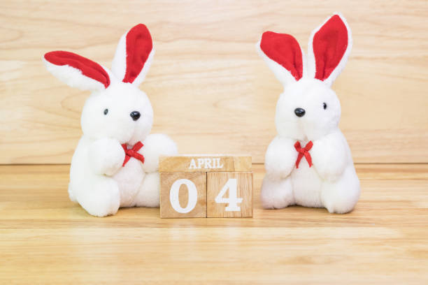 istock White rabbit doll with wood text April 4 on wood table 1303685193