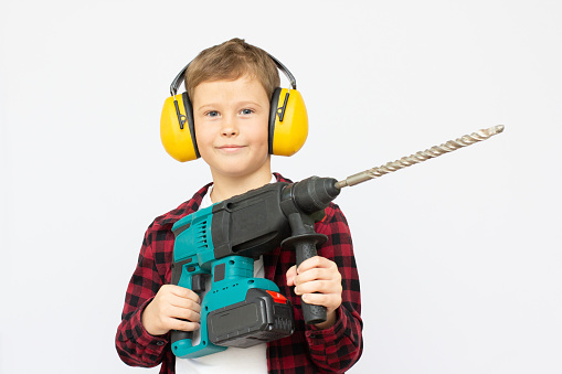 Little child holding a hammer drill unscrew, skillful little boy