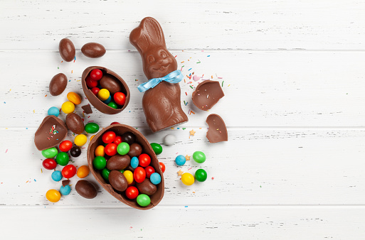 Chocolate easter eggs, choco rabbit and colorful sweets on wooden background greeting card. Top view. Flat lay with space for your greetings
