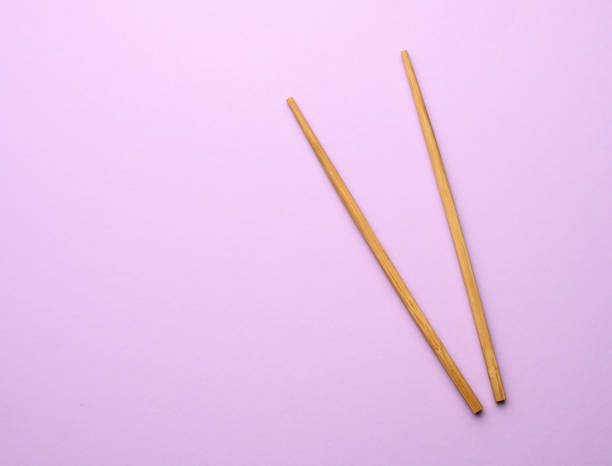 istock two wooden chopsticks on a purple background 1303685565