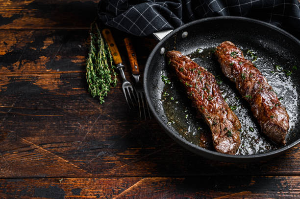 istock Grilled flank Steak in a pan.  Dark wooden background. Top view. Copy space 1303686808