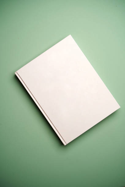 White blank book cover on green background with copy space, top view
