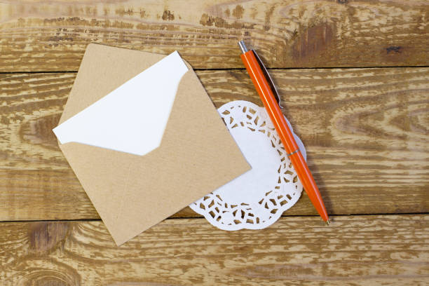 istock Simple small envelope with space for writing on a wood background with a pen close-up 1303687191