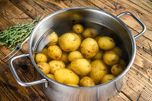Boiled baby Potatoes in a saucepan. Wooden background. Top view.