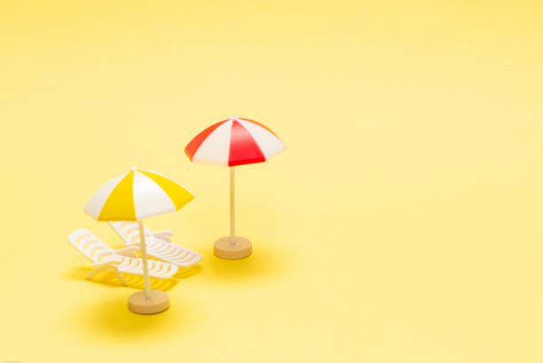 istock Two sun loungers and a red umbrella on a yellow background. 1303687583