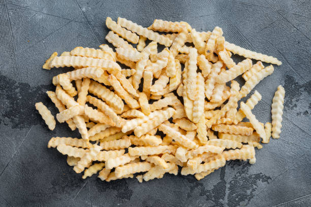 istock Frozen oven chips sliced potato, on gray background, top view flat lay 1303688348