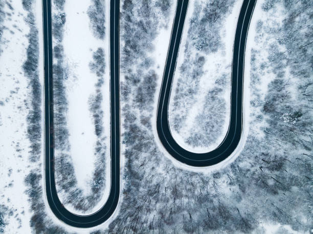 istock Curvy Windy Road in Snow Covered Forest, Top Down Aerial Drone View 1303688468