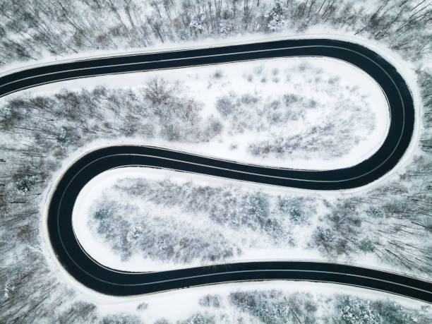 istock Curvy Windy Road in Snow Covered Forest, Top Down Aerial Drone View 1303688598