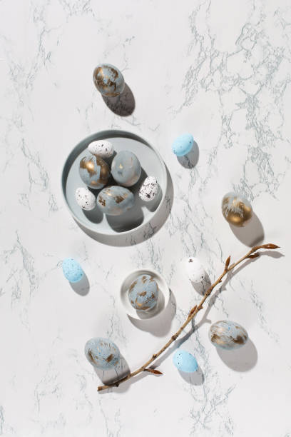 istock Easter blue golden eggs, quail eggs, tree branch on gray marble table. 1303691924