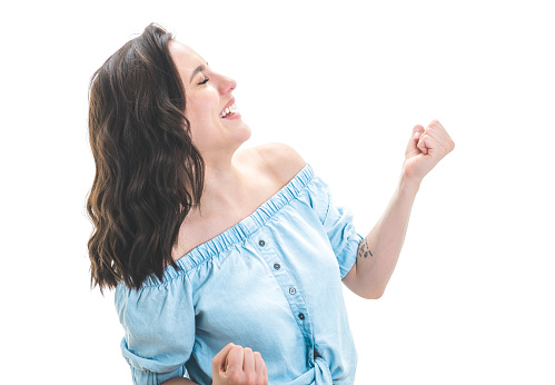 Excited beautiful young woman with opened mouth and clenched fists, isolated on white background. Surprised female person. Yes concept. Good news. Pretty girl celebrates success. Studio shot