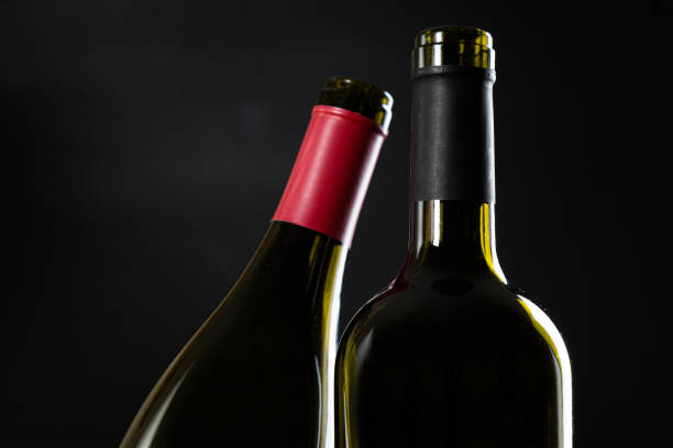 istock two open empty bottles of wine on a dark glossy background. 1303695679