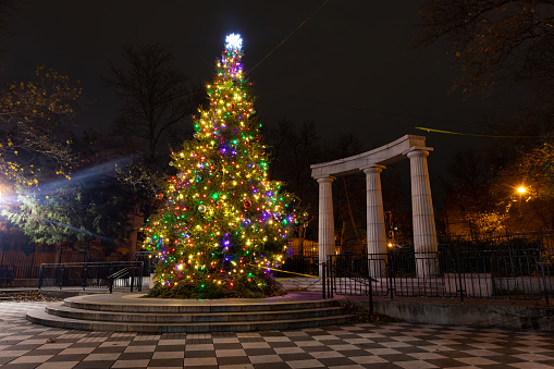 A colorful Christmas tree at night in Athens Square park in Astoria Queens of New York City with pillars
