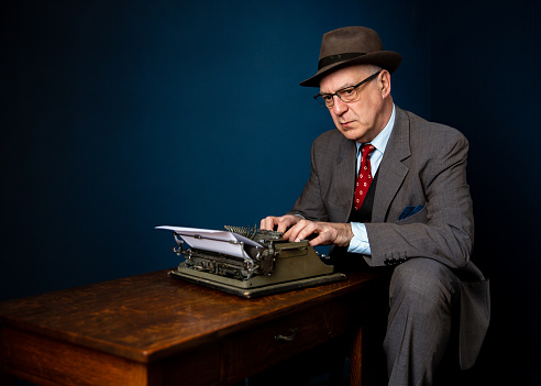 A senior vintage writer or journalist writing a news article for the paper or column in a magazine, wearing suit and hat