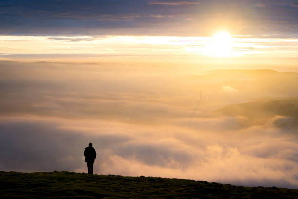 istock One single man standing on mountain alone watching sunrise silhouetted stood high above clouds 1303698522