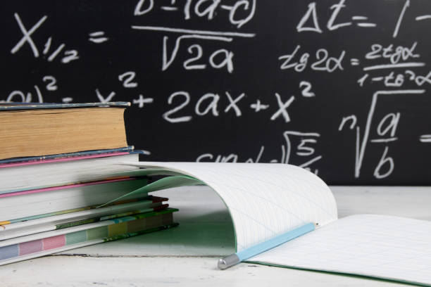 istock Books and notebook on blackboard background with mathematical formulas. Education concept. 1303699232