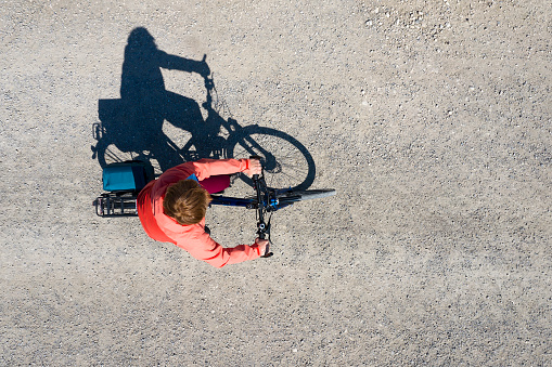Woman riding bicycle and using protective face Covid-19 mask, aerial view.