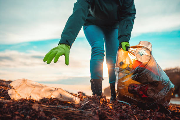 A volunteer collects garbage on a muddy beach. Close-up. The concept of Earth Day. Bottom view A volunteer collects garbage on a muddy beach. Close-up. The concept of Earth Day. Bottom view. earth day stock pictures, royalty-free photos & images