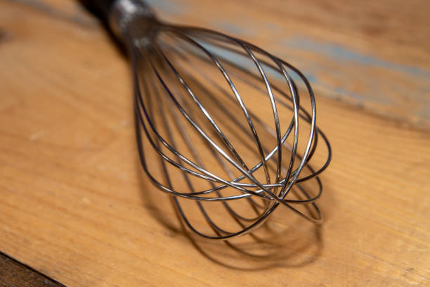 istock A kitchen metal whisk with a black handle on a wooden kitchen table 1303701292