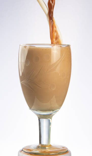 istock Coffee and milk being poured into a crystal cup at the same time, gray gradient background, selective focus. 1303701556