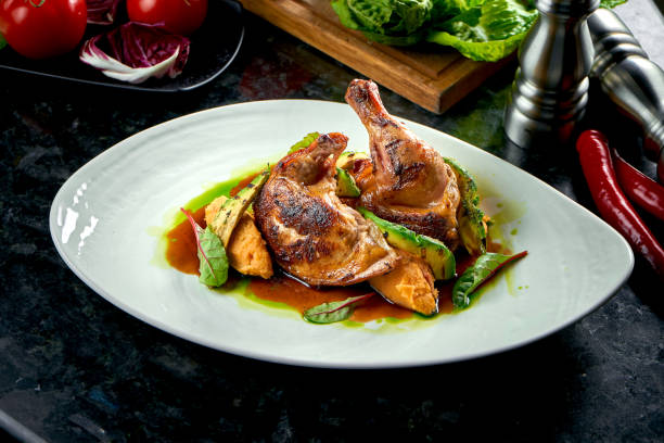 istock Fried chicken thighs with yellow and green sauce garnished with mashed potatoes and avakodos, served on a white plate. Restaurant food. Meat dish 1303703013