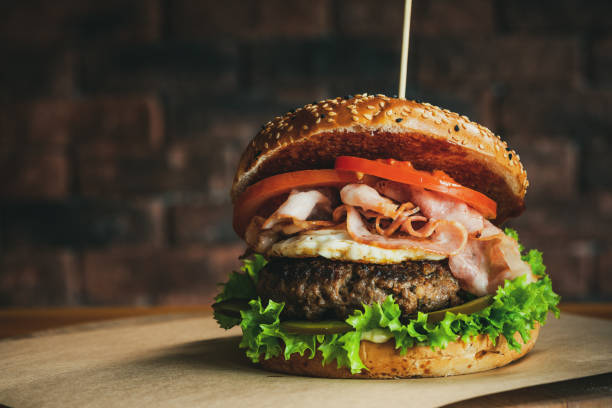 istock Tasty American Burger with BAcon Beef and Egg on Wooden Table. Brick Wall Copyspace Background 1303703274