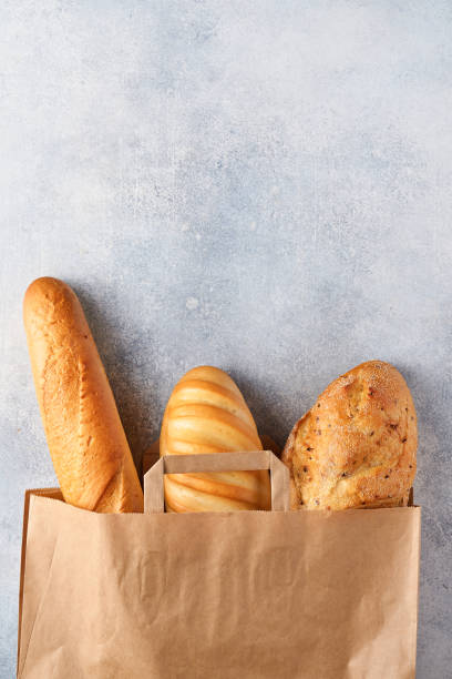 istock Mixed bread in a paper bag on light gray concrete stone table. Top view with copy space 1303703297