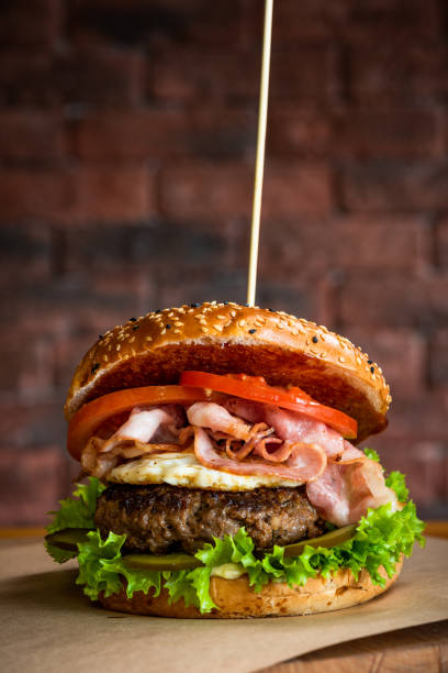 istock Tasty American Burger with BAcon Beef and Egg on Wooden Table. Brick Wall Copyspace Background 1303703915