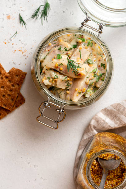 istock Pickled herring in a glass jar top view. Senapssill. 1303704279
