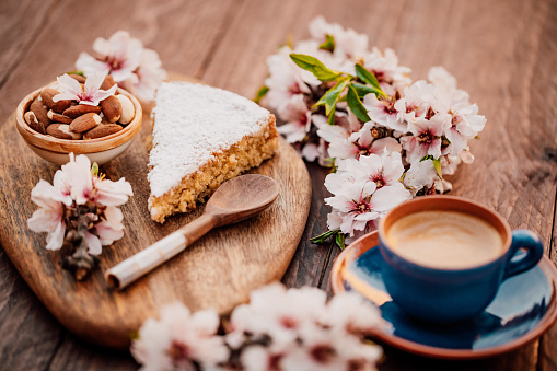Mallorcan almond cake called Gató adorned with almond blossoms and served with Spanish coffee. Creative color editing with slightly grain added. Part of a series.
