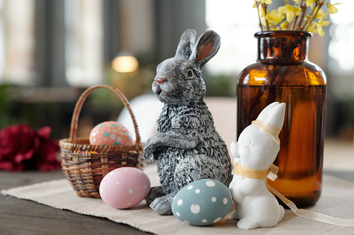 Image of ceramic rabbit with painting eggs on the table prepared for Easter