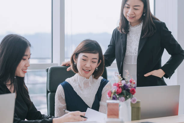 istock 3 asian chinese white collar women having discussion in open plan office looking at files 1303704721