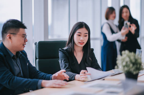 istock 2 asian chinese white collar worker having discussion in open plan office looking at files 1303704830