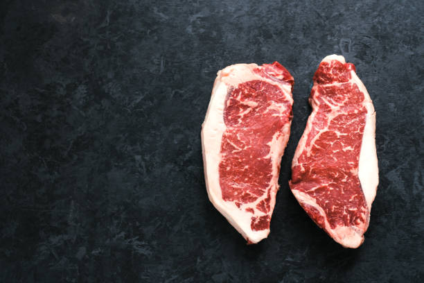 bistecca di manzo a striploin cruda di new york isolata su sfondo nero - strip steak steak beef raw foto e immagini stock