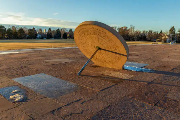 Beautiful sundial in the Cranmer Park, Denver, Colorado, with trees and Denver cityscape on background