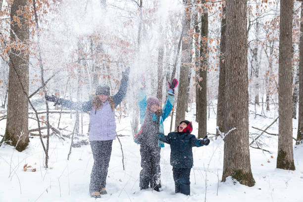 istock Three Children Playing in Winter Woods Throwing Snow 1303707076