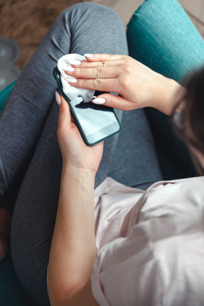istock Young woman cleaning mobile phone screen with antibacterial clot 1303707157