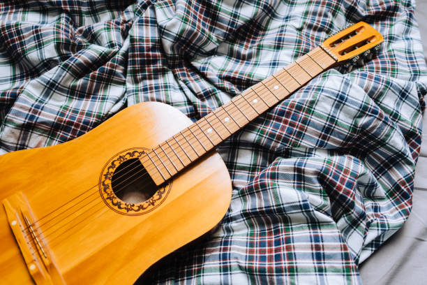 istock Wooden acoustic guitar on the bed. 1303709976