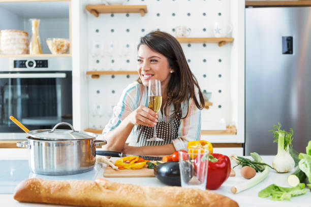istock Young woman cooking and drinking wine in kitchen 1303712881