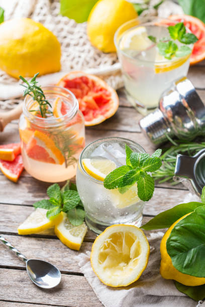 Hard seltzer cocktails with citrus fruits, zero waste bartenders accessories Hard seltzer cocktails with lemon, grapefruit, mint, rosemary and ice on a table. Summer refreshing beverage, drink with trendy zero waste accessories, bamboo straw and mesh bag. soda water glass lemon stock pictures, royalty-free photos & images