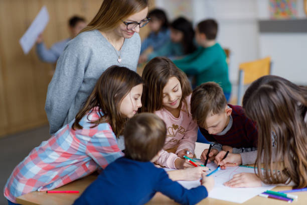istock Group of children whit teacher drawing in classroom 1303713112