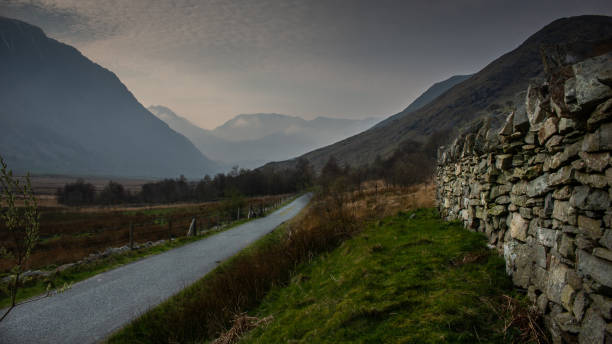 istock Road lead to the dark mountain  white cloud sky 1303713709
